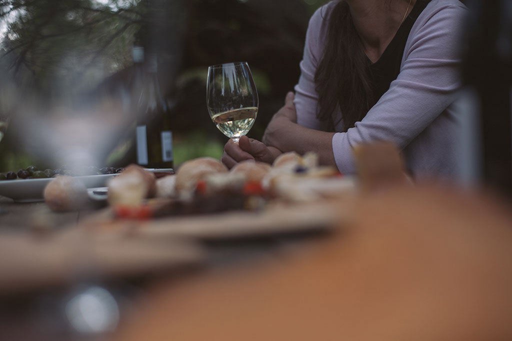 Woman with white wine glass at table with food